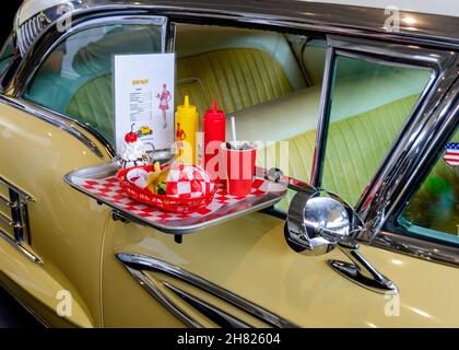 Vassoio di servizio per cena con Burger e Cola bloccato sul telaio della finestra di una classica auto americana Foto Stock