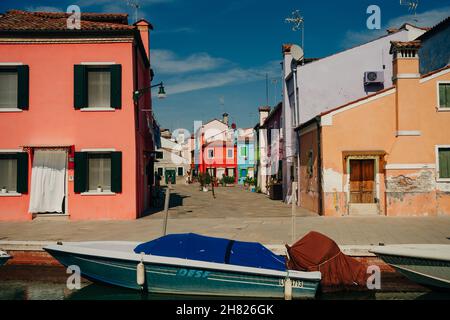 Case vivaci lungo un canale costeggiato da barche a Burano, Venezia, Italia. Foto di alta qualità Foto Stock