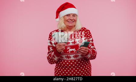 Nonna di Natale guardando smartphone sinceramente gioire vincere fortuna ricevere denaro online Foto Stock