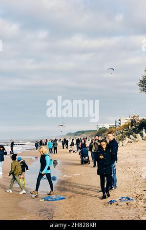 SARBINOWO, POLONIA - 15 ottobre 2017: Un colpo verticale di una spiaggia sabbiosa a Sarbinowo, Polonia, con persone che camminano vicino all'acqua in una giornata ventosa Foto Stock