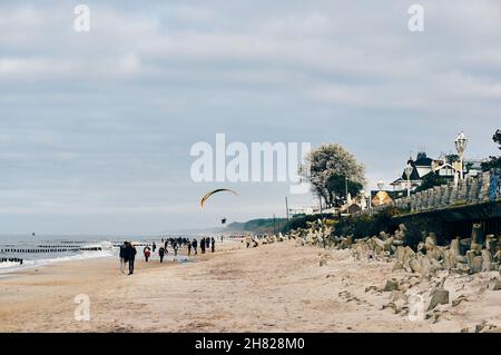 SARBINOWO, POLONIA - 15 ottobre 2017: Una spiaggia sabbiosa a Sarbinowo, Polonia con persone che camminano vicino all'acqua in una giornata ventosa Foto Stock