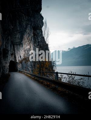 Scenario inquietante di una strada che conduce in un tunnel in una scogliera presso il lago di Walenstadt in Svizzera Foto Stock