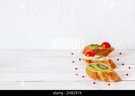 Tre mini sandwich su sfondo bianco di legno Foto Stock