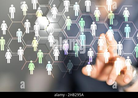 Uomo che tocca un ologramma di una rete di persone che lavorano in squadra Foto Stock