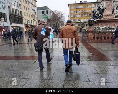 Monaco, Baviera, Germania. 26 novembre 2021. Un uomo a Monaco di Baviera, in Germania, porta un vetro divisorio attraverso Marienplatz. Il vetro di Thr ha ancora segni che indicano che è stato usato per rallentare o prevenire la diffusione di Coronavirus. (Credit Image: © Sachelle Babbar/ZUMA Press Wire) Credit: ZUMA Press, Inc./Alamy Live News Foto Stock