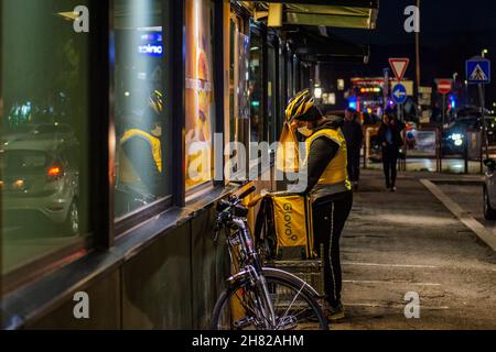 Rieti, Rieti, Italia. 24 novembre 2021. Italia, novembre 2021. Ogni giorno, soprattutto dopo il blocco in mezzo alla pandemia di emergenza sanitaria, le strade sono piene di giovani armati di zaini termici e biciclette che percorrono chilometri per consegnare pizze o menu fast food in varie parti d'Europa e Italia. La vita del pilota è tutta dietro uno smartphone, un ordine è confermato in un ristorante, pizzeria o fast food. Il pilota accetta la commissione dalla sua app e inizia a pedalare verso la casa di un utente che vuole consumare qualcosa di diverso all'interno delle pareti di Foto Stock