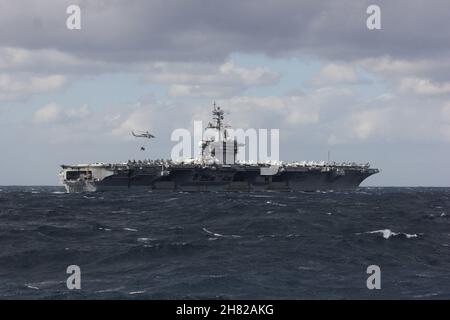 211123-N-UK628-1001 MAR DELLE FILIPPINE (NOV. 23, 2021) vettore aereo di classe Nimitz USS Carl Vinson (CVN 70) effettua un rifornimento verticale con Dry Cargo e nave munizioni USNS Matthew Perry (T-AKE-9) durante l'esercizio annuale (ANNUALEX) 2021, 23 novembre 2021. ANNUALEX è un esercizio multilaterale condotto da elementi navali della Royal Australian, Royal Canadian, German Navy, Japan Maritime Self-Defense Force e U.S. Naves per dimostrare l'interoperabilità navale e un impegno congiunto per un libero, aperto e inclusivo Indo-Pacific. (STATI UNITI Foto Navy di Sonar Technician 2a classe Ashleigh Englibert) Foto Stock