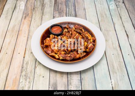 L'orecchio di maiale con salsa piccante su un piatto bianco è una sorta di razione servita in bar spagnoli che consiste di orecchio di maiale alla griglia Foto Stock