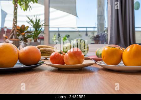 Set di piatti con frutta assortita, pomodori e persimmons Foto Stock