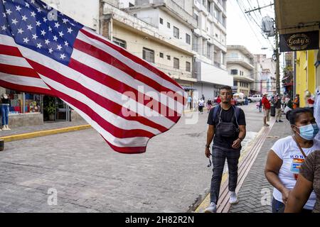 Tegucigalpa, Honduras. 26 novembre 2021. La gente cammina vicino alla bandiera degli Stati Uniti.la Repubblica dell'Honduras terrà le elezioni generali per scegliere un nuovo insieme di presidente, congresso e governi municipali il 28 novembre. Credit: SOPA Images Limited/Alamy Live News Foto Stock