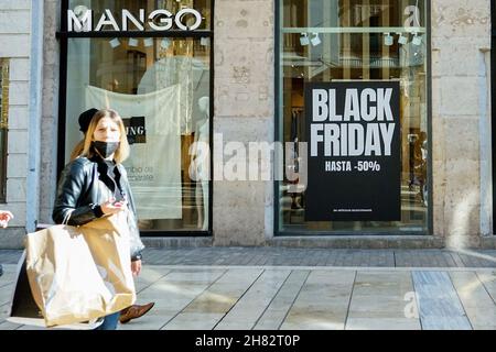 Malaga, Spagna. 26 novembre 2021. Una donna che porta con sé una borsa per lo shopping passa davanti a un negozio Mango che offre uno sconto del 50% su un Black Friday a Malaga.in 2021, il commercio online è cresciuto del 71% dopo che i consumatori temono la folla e incontri sociali in mezzo alla pandemia del convivid-19. Credit: SOPA Images Limited/Alamy Live News Foto Stock