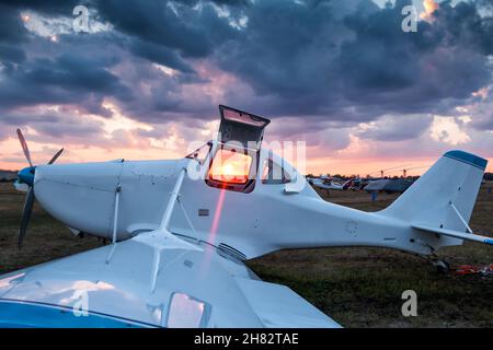 Primo piano di aeroplano agricolo bianco con pozzetto aperto sullo sfondo di un pittoresco tramonto Foto Stock