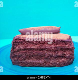 Vista laterale di una torta al cioccolato fondente su sfondo turchese Foto Stock