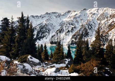 Bellissimo paesaggio di lago di montagna con ghiaccio blu e foresta di abete rosso in inverno Foto Stock