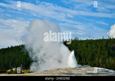 Erutting Geyser Old Faithful nel più antico parco nazionale del mondo - Yellowstone National Park, Wyoming, USA contro il cielo nuvoloso Foto Stock