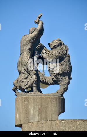 Skulptur auf der Gallusbrücke vor den Toren von Wangen im Allgäu zeigt den Kampf von HL.Gallus mit dem Bären gegen den blauen Himmel Foto Stock