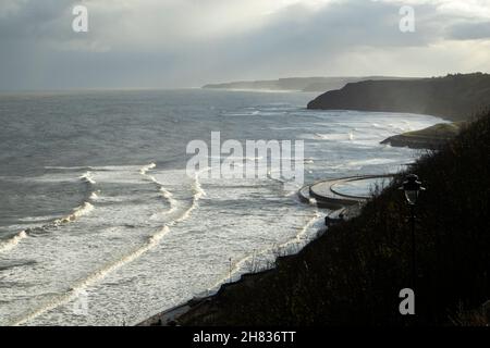 Una tempesta invernale soffia il surf sulla costa del Mare del Nord sotto Scarborough. Guardando verso il basso verso Flamborough Head, la fine del percorso costiero Foto Stock