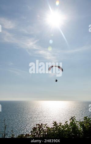 Parapendio sopra il mare a Barton on on Sea, Hampshire, Inghilterra, Regno Unito Foto Stock