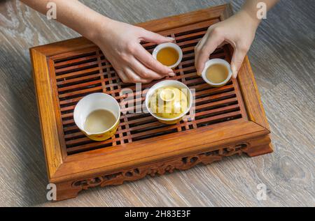 Tavolo in legno con vista dall'alto per la cerimonia del tè sullo sfondo. Donna e bambino che tengono una tazza di tè. Foto di alta qualità Foto Stock