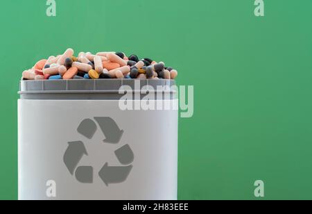 Pieno di pillole scadute e medicinali nel cestino con il simbolo di riciclaggio. Pillole di scarto raccolte per essere riciclate. Concetto di gestione dei rifiuti. Foto Stock