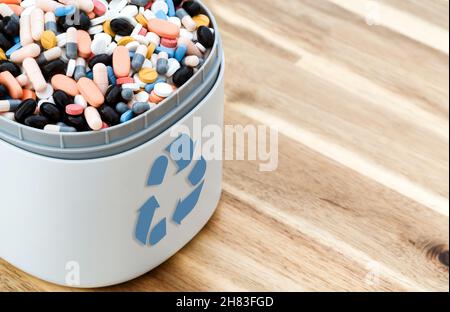 Pieno di pillole scadute e medicinali nel cestino con il simbolo di riciclaggio. Pillole di scarto raccolte per essere riciclate. Concetto di gestione dei rifiuti. Foto Stock