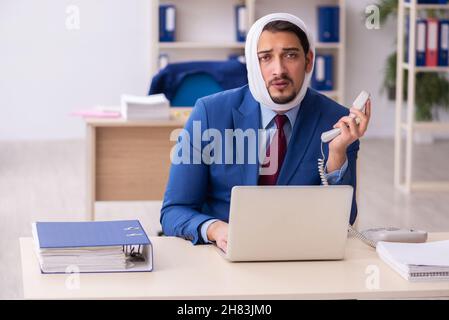 Giovane impiegato di uomini d'affari che soffre di mal di denti sul posto di lavoro Foto Stock