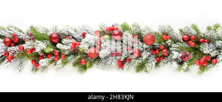 Banner natalizio con baubles rossi in fila su rami innevati di abete sempreverdi isolati su sfondo bianco. Dimensioni ampie. Foto Stock