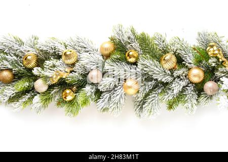 Banner natalizio con baubles d'oro in fila su rami innevati di abete sempreverdi isolati su sfondo bianco. Dimensioni ampie. Foto Stock
