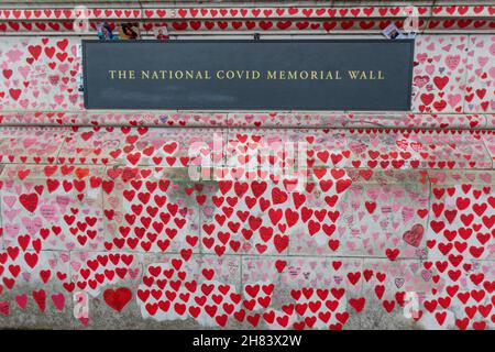 Londra, Regno Unito. 27 novembre 2021. 27 novembre 2021. Una sezione toccante del National COVID Memorial Wall di Londra, con centinaia di cuori rossi e rosa dipinti a mano, ognuno dei quali simboleggia una vita persa a causa della COVID-19 nel Regno Unito. La targa centrale recita “IL MURO NAZIONALE del COVID MEMORIAL”, circondato da messaggi personali e tributi. Il muro National Covid Memorial sulla riva sud del Tamigi, di fronte alla camera del Parlamento. Crediti: Penelope Barritt/Alamy Live News Foto Stock