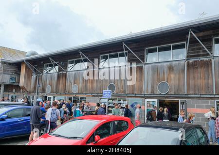 Padstow, Regno Unito - Luglio 2021: Clienti che fanno la fila fuori da Stein's Deli sul lungofiume di Padstow. Foto Stock