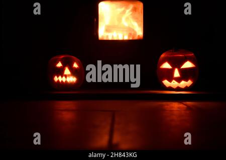 Teste di zucca che sorvegliano il fuoco di ceppo Foto Stock