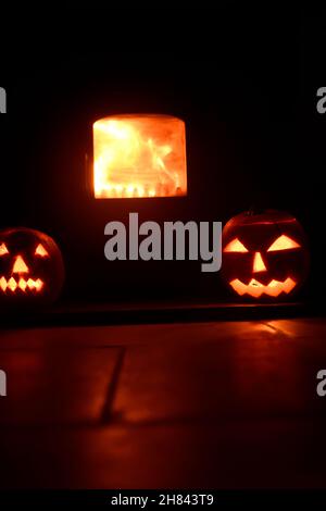 Teste di zucca che sorvegliano il fuoco di ceppo Foto Stock