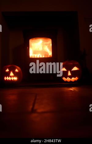 Teste di zucca che sorvegliano il fuoco di ceppo Foto Stock