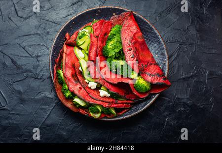 Deliziose frittelle di barbabietole con broccoli e cetrioli su sfondo ardesia. Cibo vegetariano Foto Stock