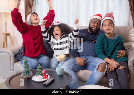Felicità famiglia africana guardare film con entusiasmo e divertimento nel soggiorno per il tempo libero con comfort a casa il giorno di Natale, papà e mamma e dau Foto Stock