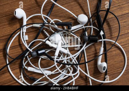 Cuffie aggrovigliate su un tavolo di legno Foto Stock