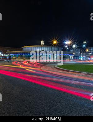 Una lunga esposizione notturna mostra le auto che viaggiano intorno all'isola del traffico alla stazione della metropolitana Southgate sulla linea metropolitana di Londra piccadilly Foto Stock