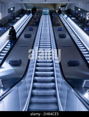 Persone che viaggiano sulle scale mobili della stazione della metropolitana di Battersea Power Station sulla rete della metropolitana di Londra di notte sull'estensione della linea nord Foto Stock