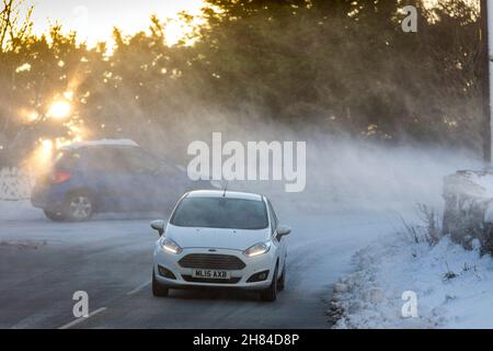 Neve pesante e venti alti come Storm Arwen morde nei Pennines vicino Queensbury, West Yorkshire, Inghilterra, Regno Unito rendendo le condizioni di guida difficili e pericolosi - i venti alti hanno influenzato le alimentazioni elettriche e la sta soffiando neve attraverso le strade. La neve soffiata su Giles Hill Lane, Shelf rende difficile la guida. Foto Stock