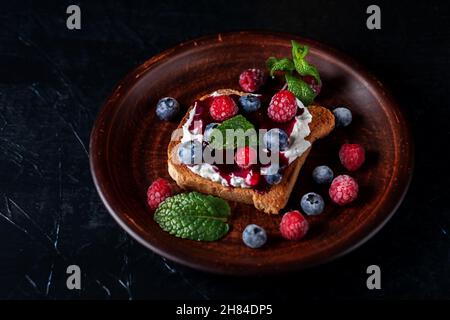 Bruschetta con formaggio, marmellata, lamponi freschi e mirtilli Foto Stock