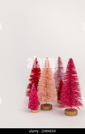 Sei Mini Pink e Red bottle Brush alberi di Natale su sfondo bianco con spazio negativo Foto Stock