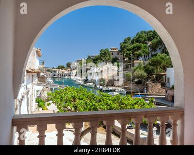 Cala Figuera Mallorca vista porto incorniciata da una vacanza arco villa con vista scena di barche da pesca case e ville, Maiorca Baleari Spagna Foto Stock