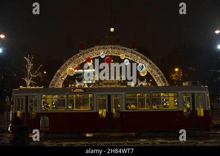 Ingresso frontale della famosa fiera di Natale del Municipio di Vienna, chiusa durante la chiusura a chiave di Covid del 2021 con un vecchio tram rosso durante la sera. Foto Stock