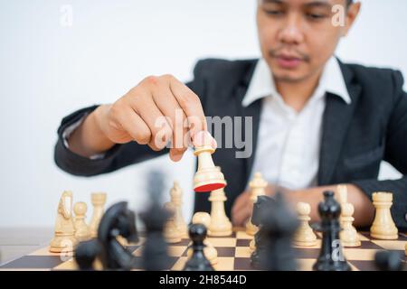 Maschio mano che tiene la pedina a passo mentre gioca a scacchi Foto Stock