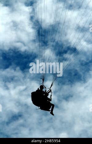 due persone in parapendio contro la luce nei cieli nuvolosi Foto Stock