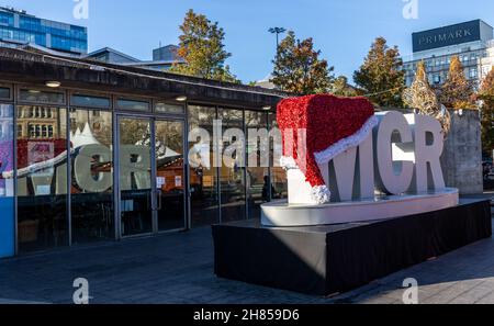 MCR con Santa Hat e Golden Manchester Bee in mostra con finestra relflection in Piccadilly Gardens, Manchester, Inghilterra, Regno Unito. 2021 Foto Stock