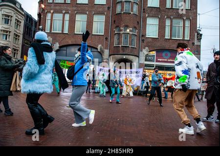 Amsterdam, Paesi Bassi. 27 novembre 2021. Un gruppo di attivisti XR è visto ballare durante la dimostrazione.Extinction Rebellion ha organizzato nel centro di Amsterdam una sfilata di moda, per mimare la moda veloce e per portare l'attenzione alle pratiche di sfruttamento, profitto-orientato, e greenwashing del settore della moda veloce. Gli attivisti del clima marciarono attraverso le principali strade dello shopping danzando e indossando abiti riparati e di seconda mano. (Foto di Ana Fernandez/SOPA Images/Sipa USA) Credit: Sipa USA/Alamy Live News Foto Stock