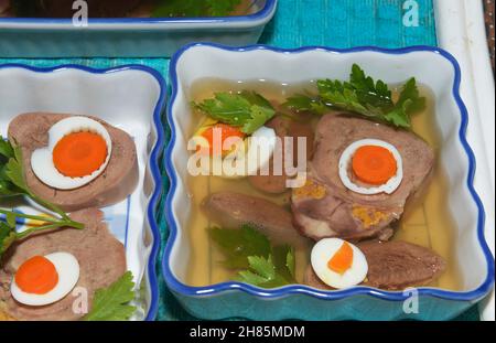 Jelly brodo viene colata dalla siviera cucchiaio in stampo con ingredienti della lingua in bellavista piatto che sono disponendo in ceramica rettangolare piatti di insalata. Foto Stock