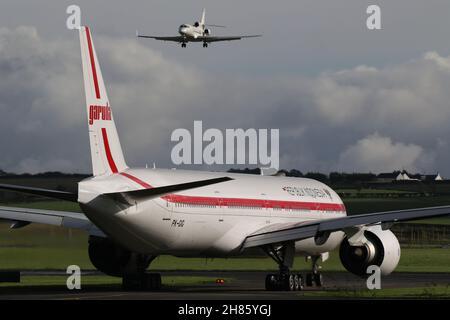 PK-GIG, un Boeing 777-3U3ER gestito da Garuda Indonesia, attende la partenza dall'aeroporto internazionale di Prestwick in Ayrshire, Scozia, come OO-LUM, un Dassault Falcon 7X operato dall'Aeronautica militare belga entra a terra. Gli aerei si trovavano in Scozia per portare i delegati al summit COP26 sui cambiamenti climatici che si teneva nella vicina città di Glasgow. Foto Stock