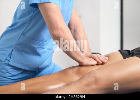 Primo piano del terapista che massaggiano la gamba del giovane uomo. Foto di alta qualità. Foto Stock